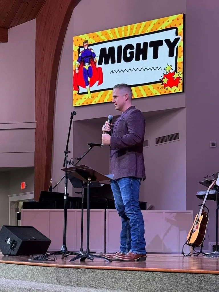 Aaron speaking beneath a superhero slide that reads “Mighty”