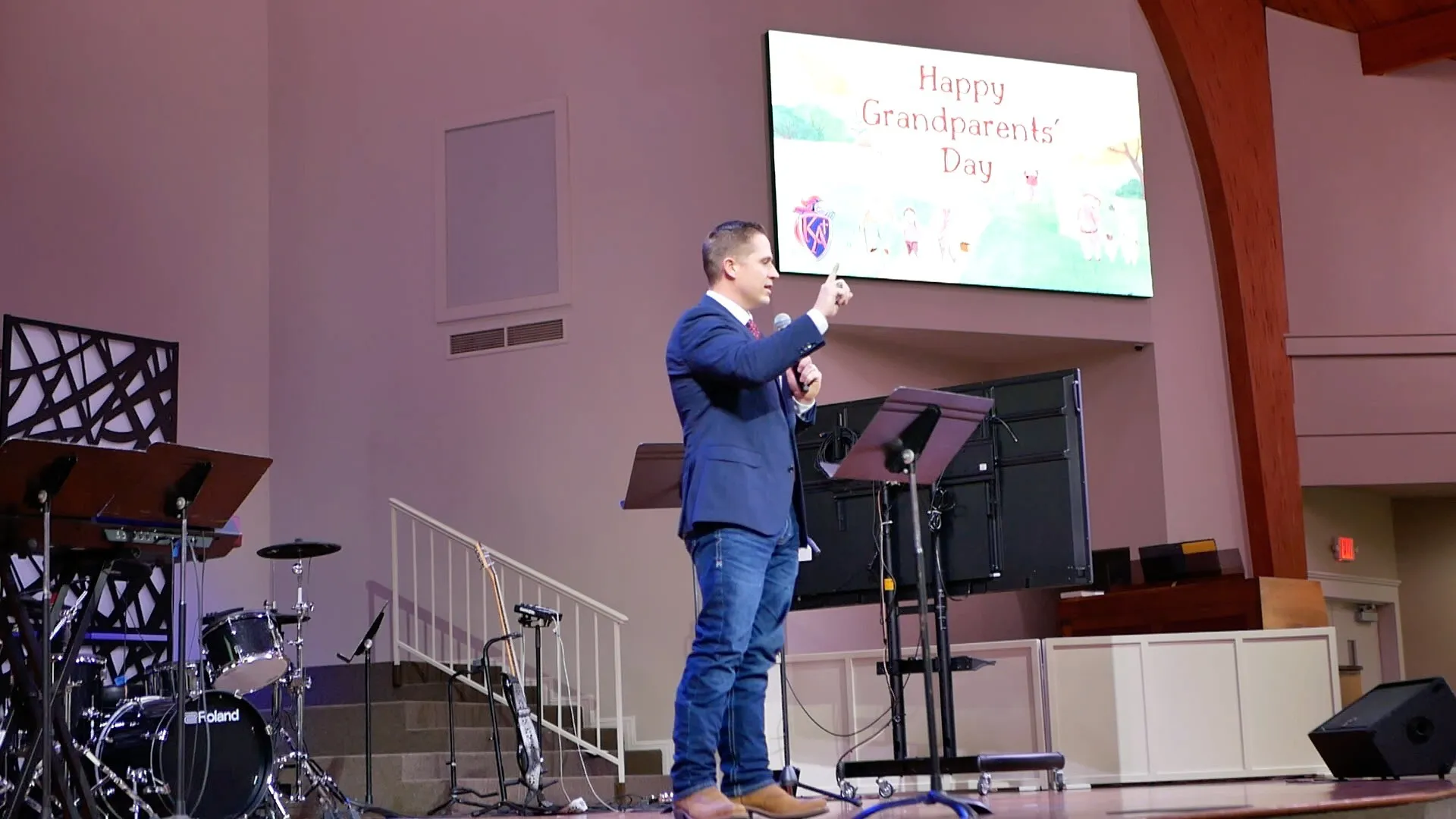 Aaron speaking on stage at a King’s Academy Grandparents Day gathering
