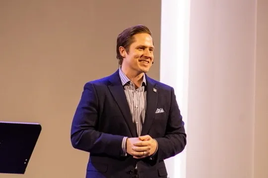 Aaron smiling on stage during a talk